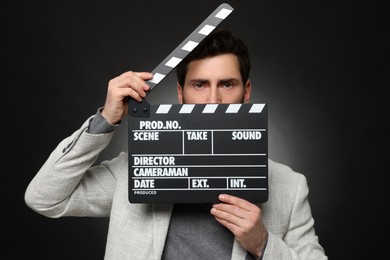Photo of Adult actor holding clapperboard on black background