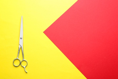 Hairdresser's scissors on color background, top view. Space for text