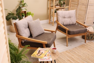 Photo of Lounge area interior with comfortable armchairs and beautiful houseplants