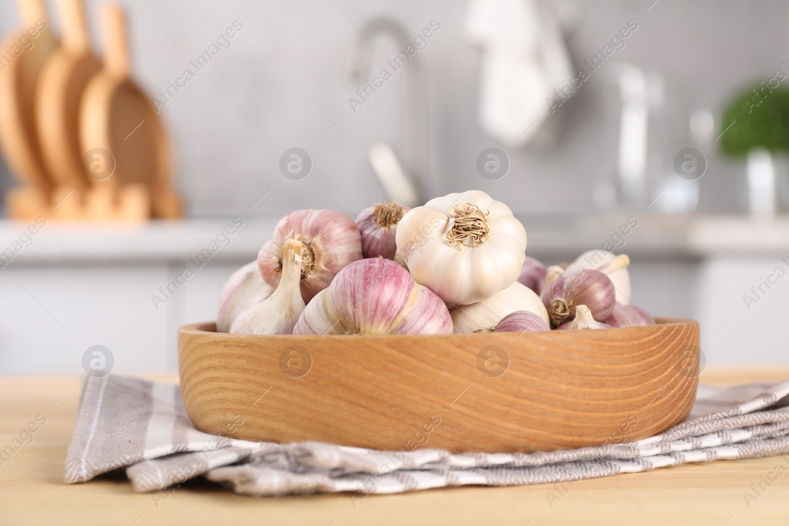 Photo of Bowl of fresh raw garlic on wooden table in kitchen