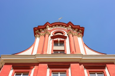 Beautiful building with weather vane on roof against blue sky, low angle view