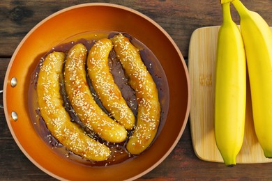 Delicious fresh and fried bananas on wooden table, flat lay