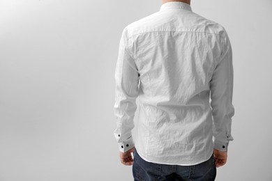 Man wearing rumpled shirt on white background, back view