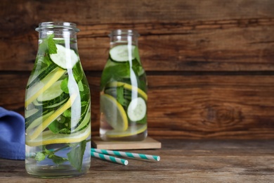 Refreshing water with cucumber, lemon and mint on wooden table. Space for text
