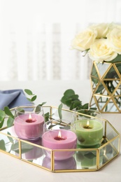 Tray with burning candles and eucalyptus on light table, space for text