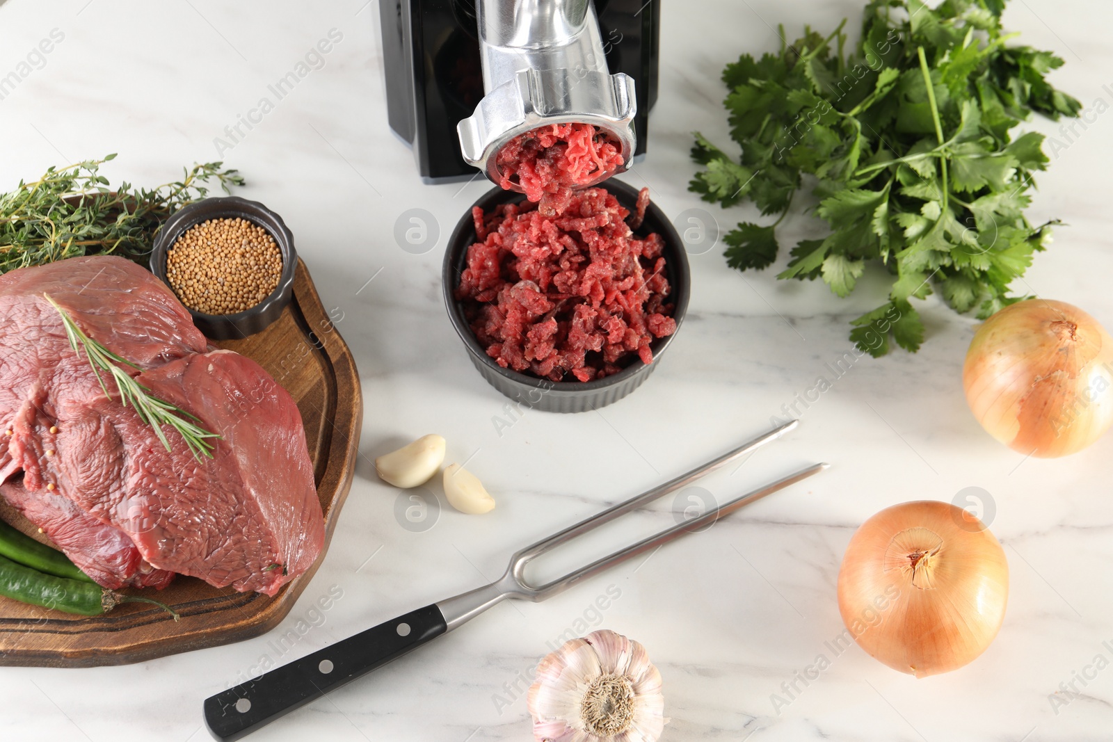 Photo of Electric meat grinder with beef mince and products on white marble table in kitchen, above view