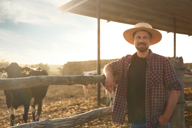 Photo of Worker standing near cow pen on farm. Animal husbandry