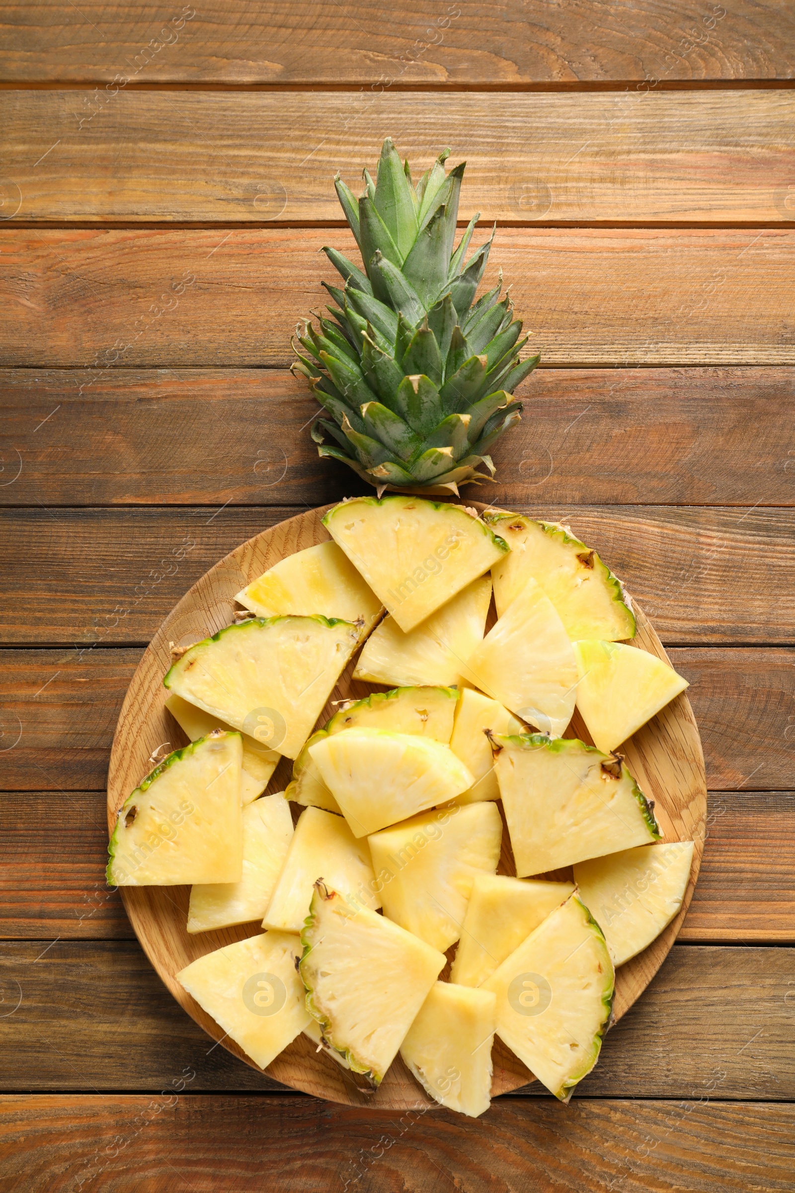 Photo of Plate with fresh sliced pineapple on wooden background