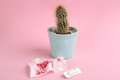 Photo of Cactus, suppository and sheet of toilet paper with blood on pink background. Hemorrhoid problems