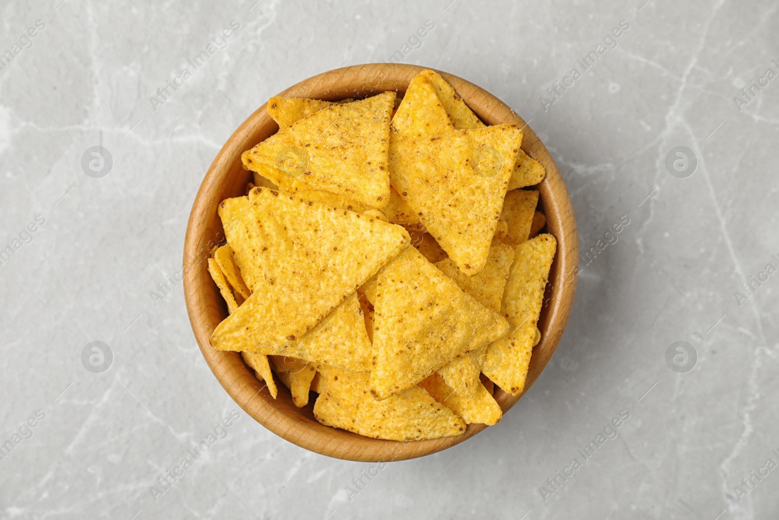 Photo of Wooden bowl with tasty Mexican nachos chips on grey table, top view