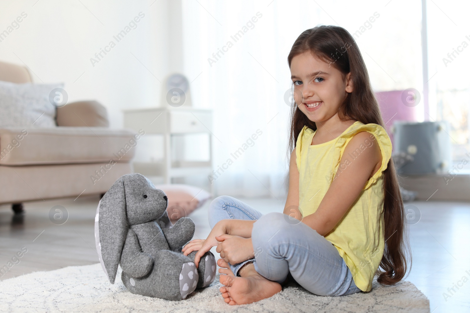 Photo of Cute little child playing with toy bunny on floor indoors. Space for text