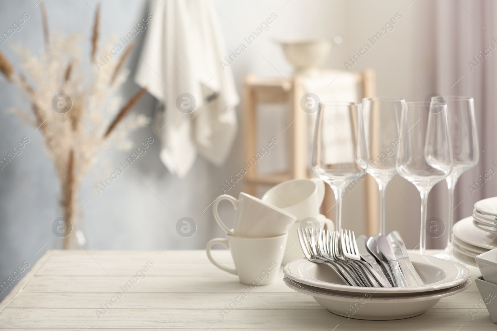 Photo of Set of clean dishware, cutlery and wineglasses on white table indoors. Space for text