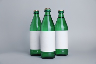 Photo of Glass bottles with soda water on light background