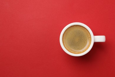 Aromatic coffee in cup on red background, top view. Space for text