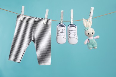 Photo of Striped baby pants, shoes and crochet toy drying on washing line against turquoise background