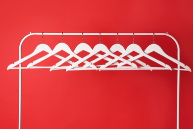 Photo of White clothes hangers on metal rack against red background