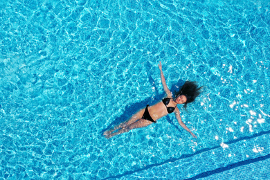 Image of Beautiful young woman swimming in pool, top view