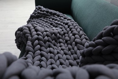 Photo of Dark grey chunky knit blanket on sofa indoors, closeup