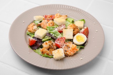 Delicious Caesar salad with shrimps on white tiled table, closeup