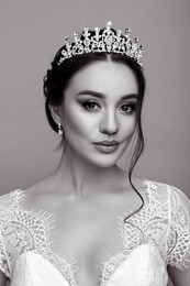 Beautiful young woman wearing luxurious tiara on grey background. Black and white effect