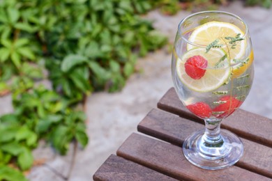 Delicious refreshing lemonade with raspberries on wooden table outdoors, space for text