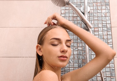 Beautiful young woman taking shower at home