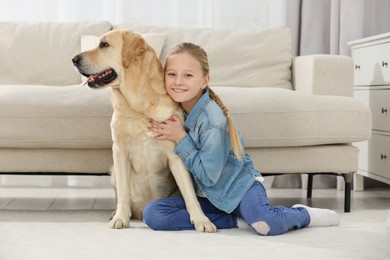 Photo of Cute child hugging her Labrador Retriever on floor at home. Adorable pet