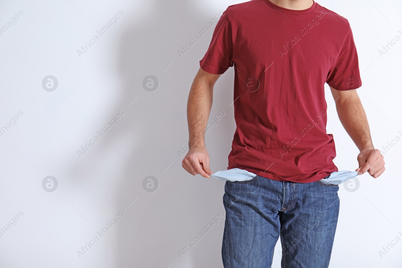 Photo of Man showing empty pockets on light background, closeup. Space for text