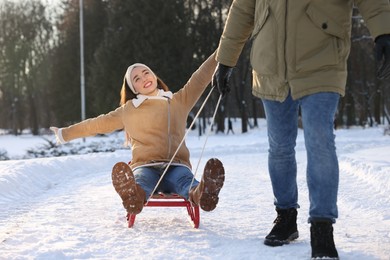 Man pulling his girlfriend in sleigh outdoors on winter day