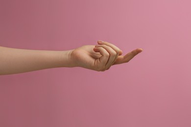 Woman showing index finger on pink background, closeup