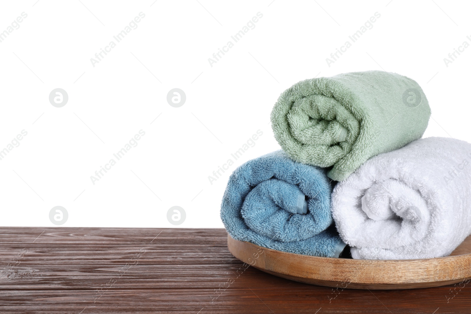 Photo of Fresh towels on wooden table against white background. Space for text