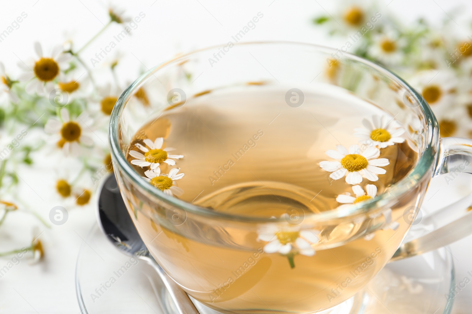 Photo of Fresh chamomile tea in cup on white table, closeup