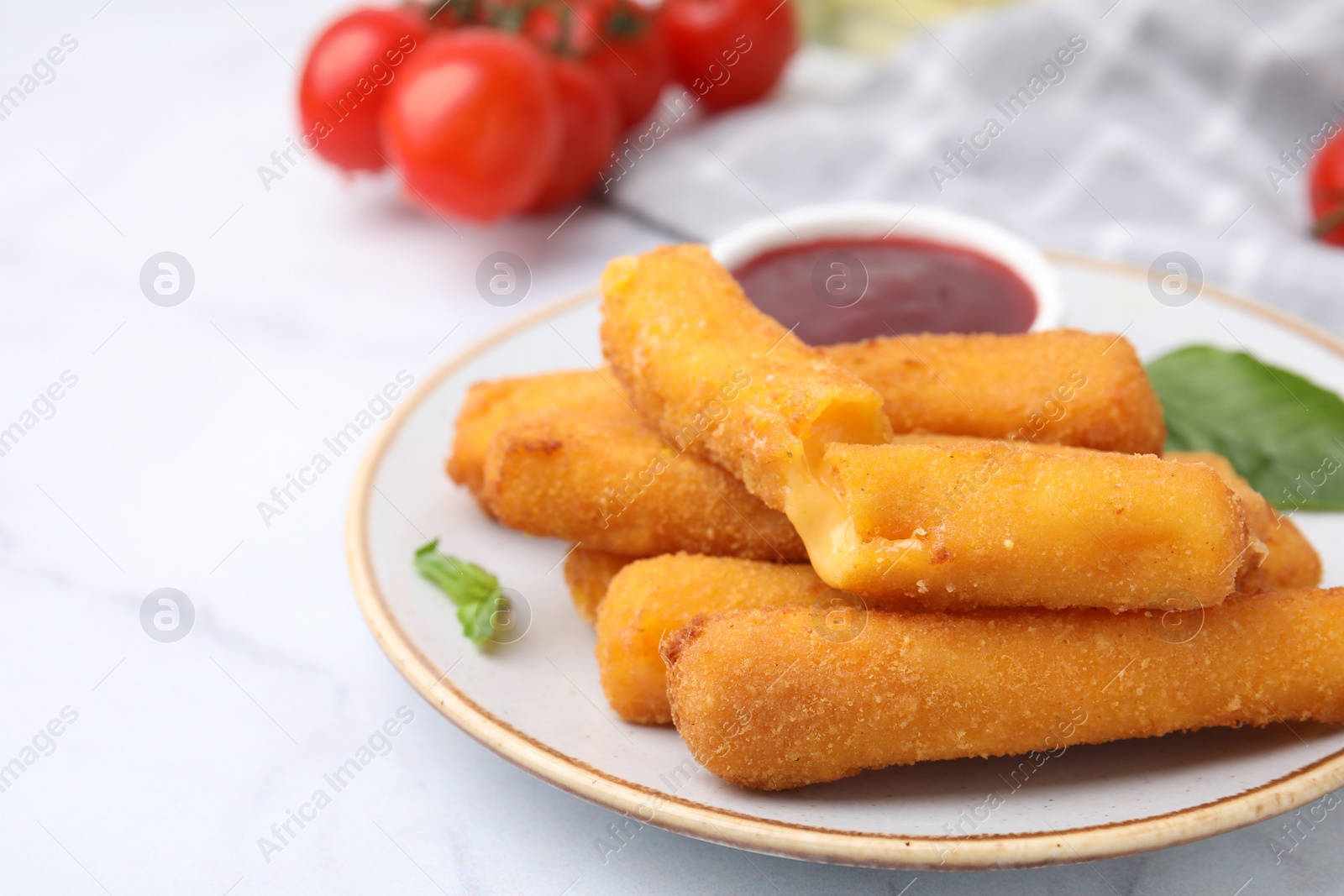 Photo of Tasty fried mozzarella sticks with tomato sauce on white table, space for text