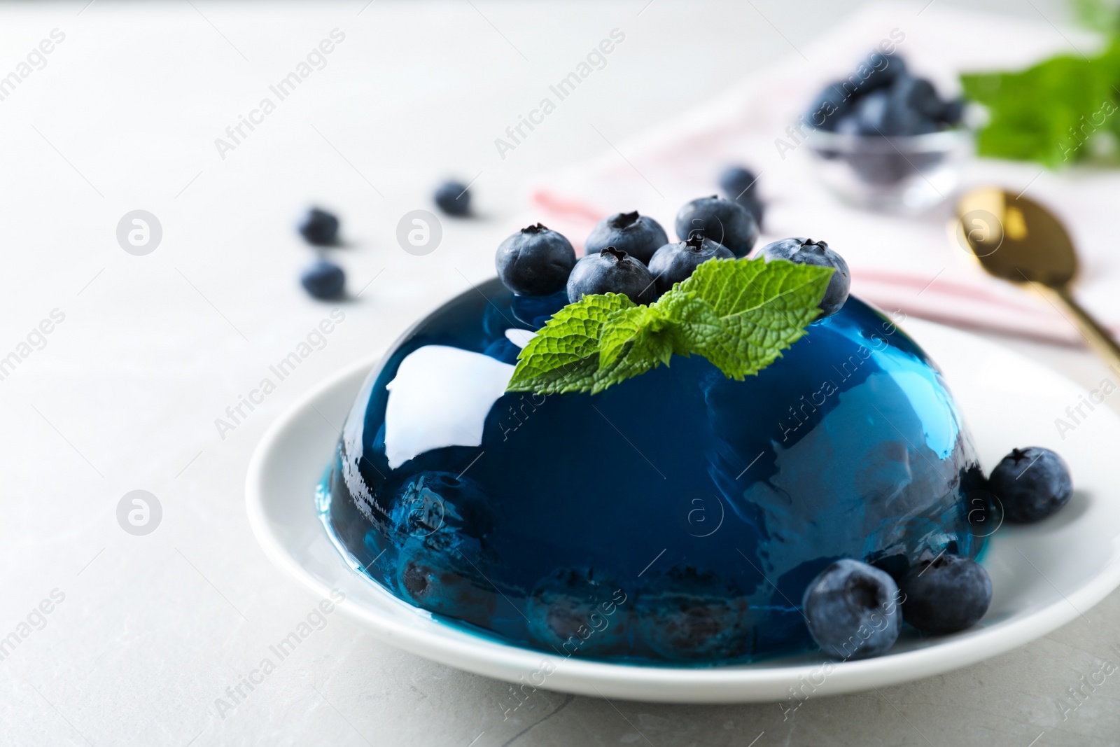 Photo of Delicious jelly with blueberries and mint on grey table