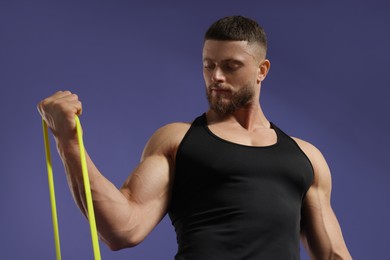 Muscular man exercising with elastic resistance band on purple background