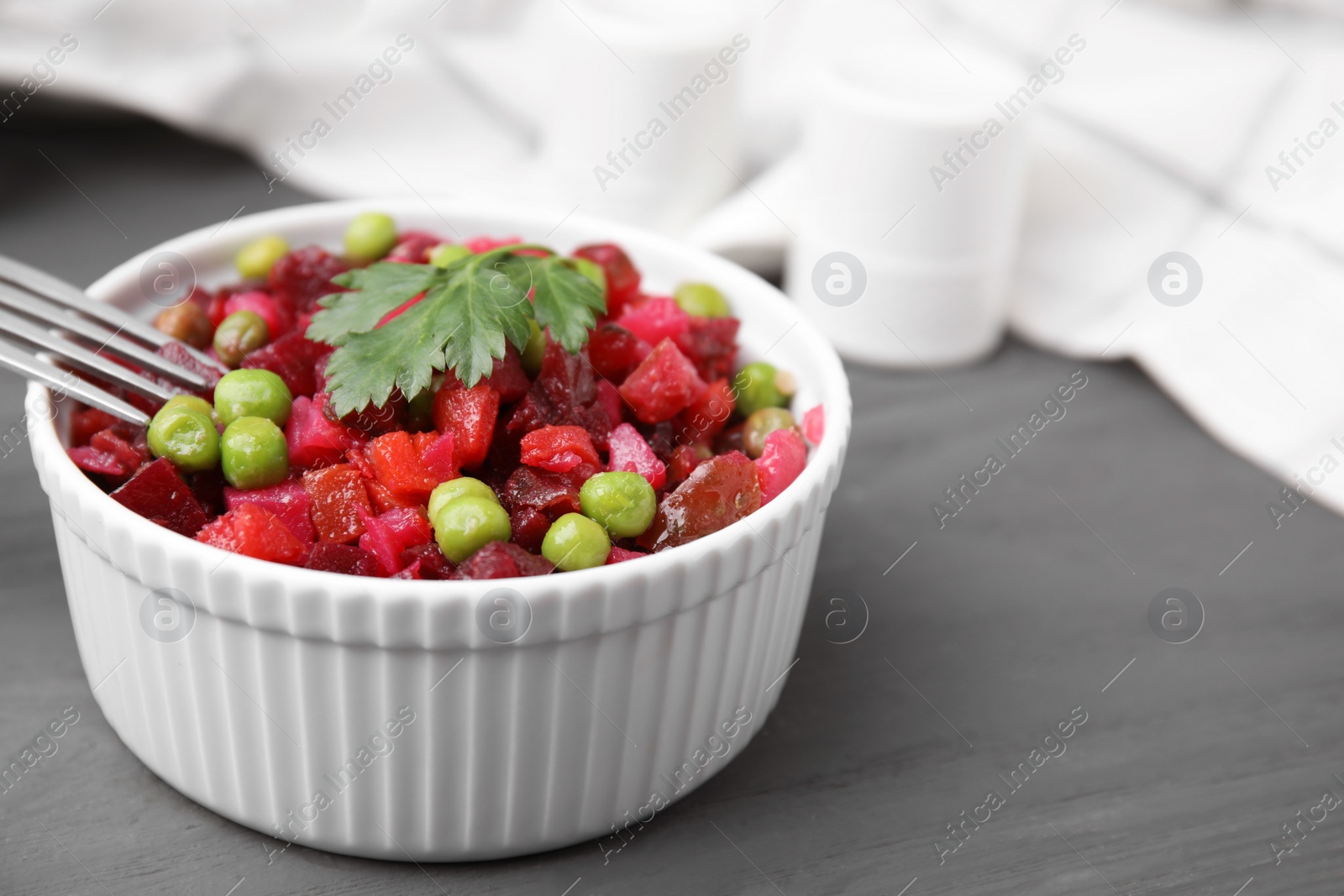 Photo of Delicious vinaigrette salad on grey wooden table, closeup. Space for text