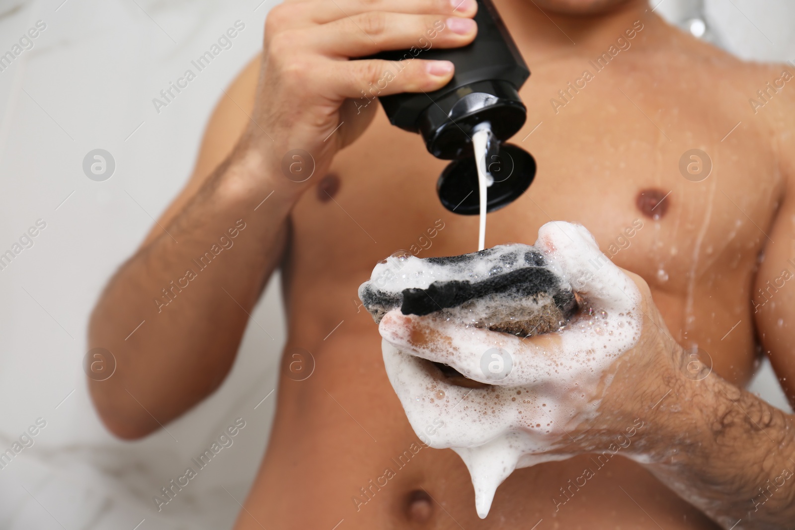 Photo of Man applying gel onto sponge in shower at home, closeup