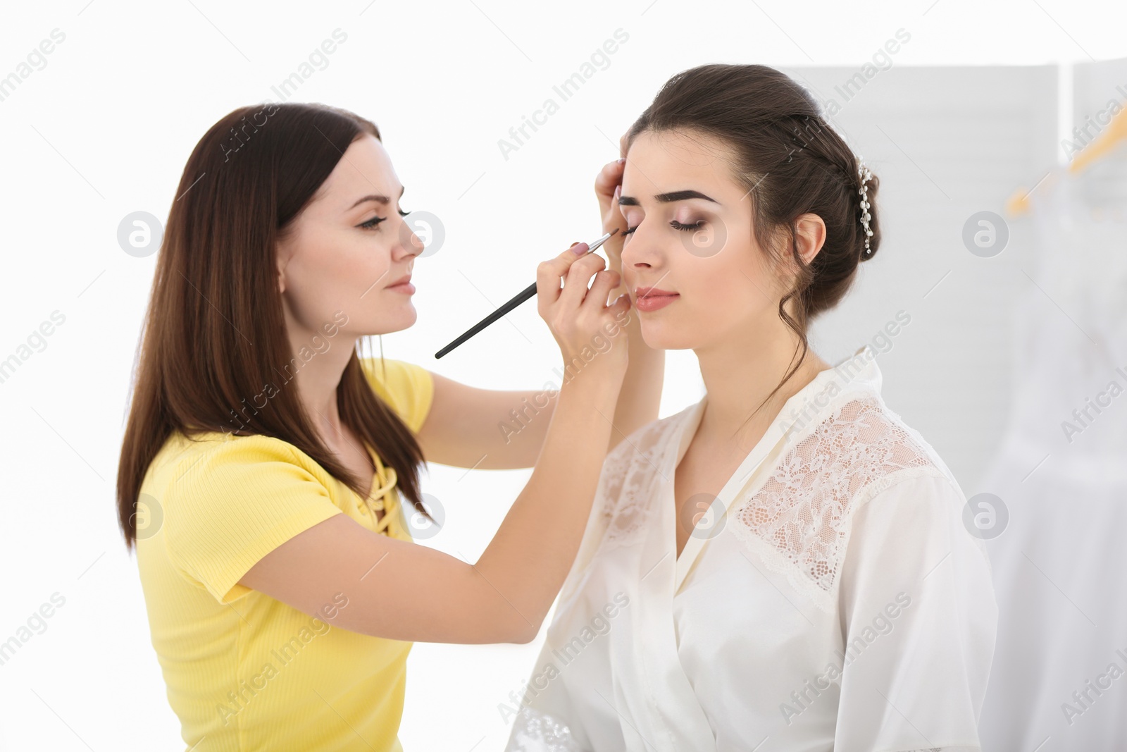 Photo of Professional makeup artist working with young woman in salon