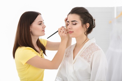 Photo of Professional makeup artist working with young woman in salon
