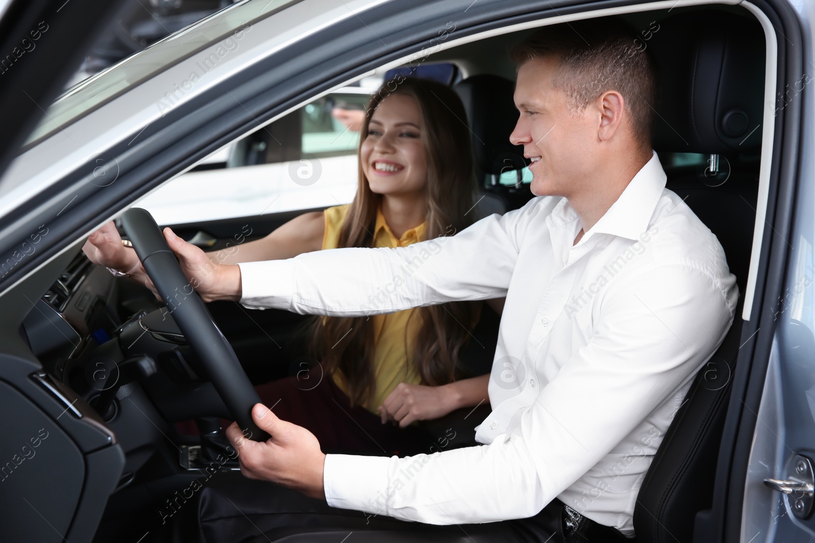 Photo of Saleswoman consulting client in auto at car dealership
