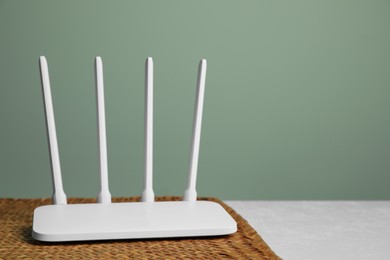 Photo of New modern Wi-Fi router on white table near green wall, space for text