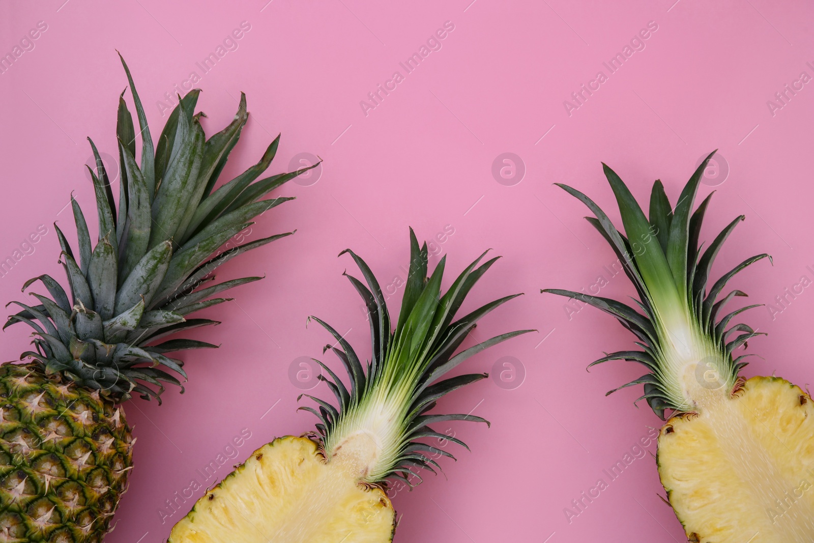 Photo of Whole and cut ripe pineapples on pink background, flat lay