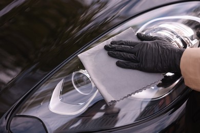 Photo of Woman wiping her modern car with rag, closeup