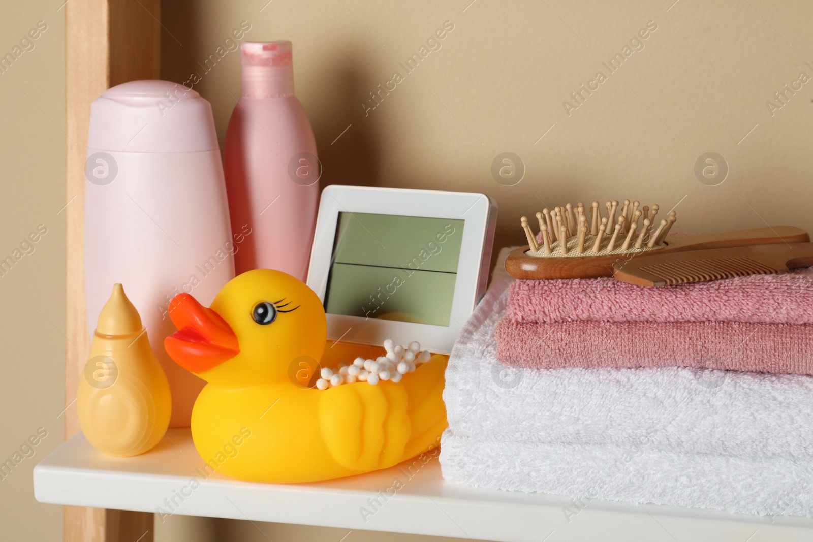 Photo of Towels, toy and baby accessories on white rack