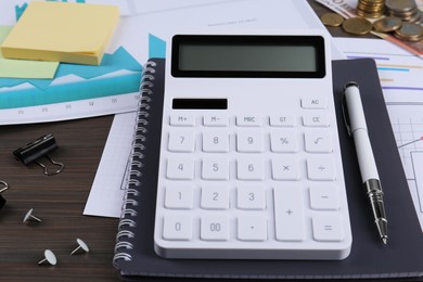 Calculator, notebook, papers, notes, pen and money on wooden table. Pension planning