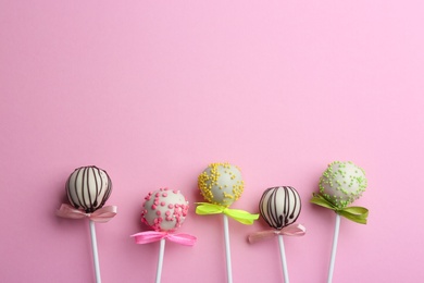 Photo of Different tasty cake pops on light pink background, flat lay. Space for text