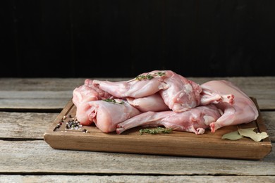 Photo of Fresh raw rabbit meat and spices on wooden table
