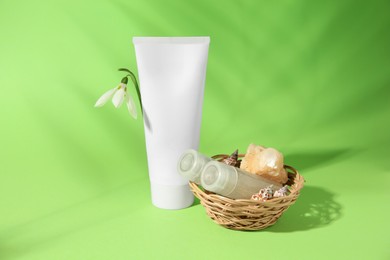 Photo of Cream, shampoo samples, stone, seashells and snowdrop flower on light green background