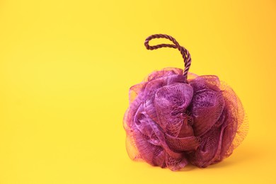 Photo of Purple shower puff on yellow background, space for text