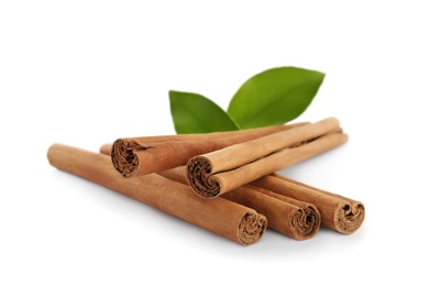 Aromatic dry cinnamon sticks and green leaves on white background